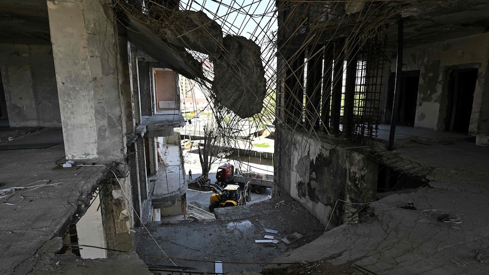 Des ouvriers nettoient des débris devant un immeuble résidentiel endommagé par une frappe aérienne le mois précédent dans la ville portuaire d'Odessa, sur la mer Noire, le 20 mai 2022. 