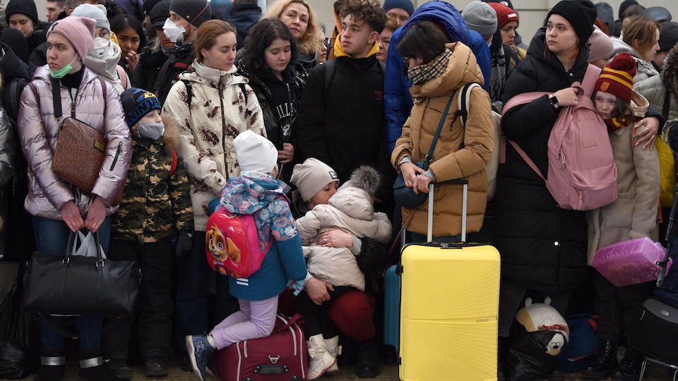 Une femme entourée de bagages enlace un enfant. 