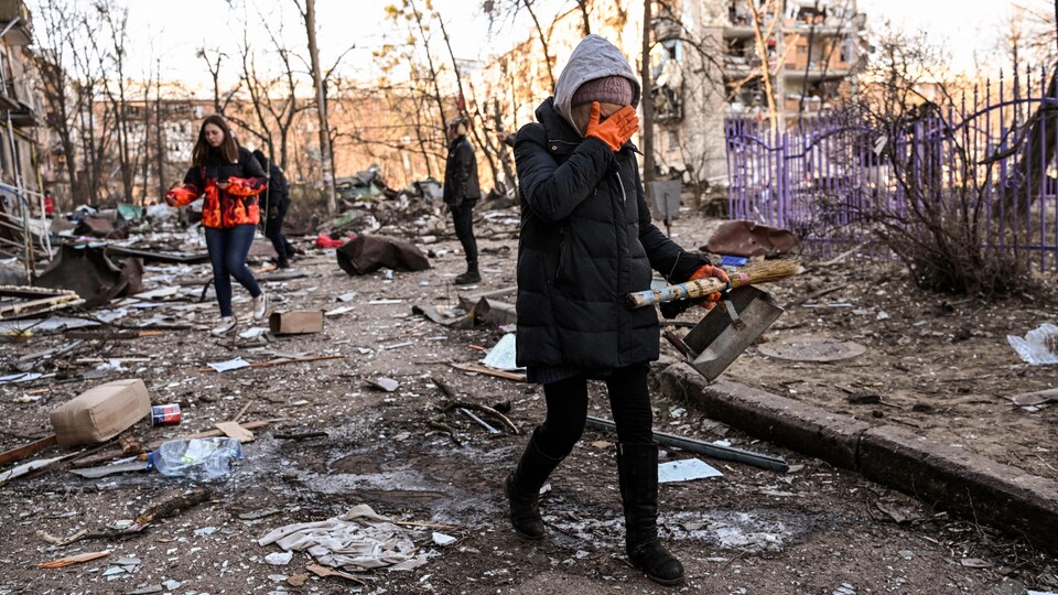 Une femme quitte la zone où un immeuble résidentiel de cinq étages s'est partiellement effondré après un bombardement à Kiev.