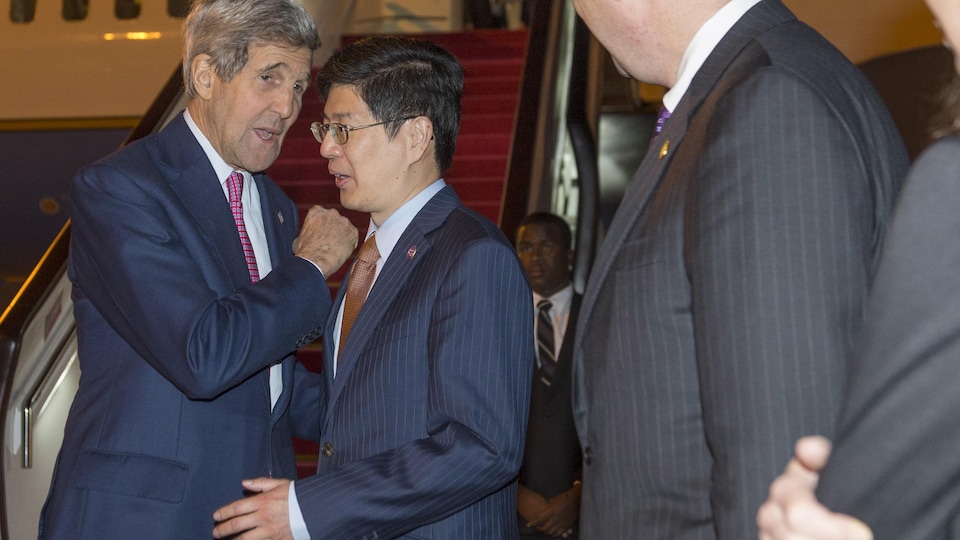 Cong Peiwu est debout devant John Kerry, près d'un avion.