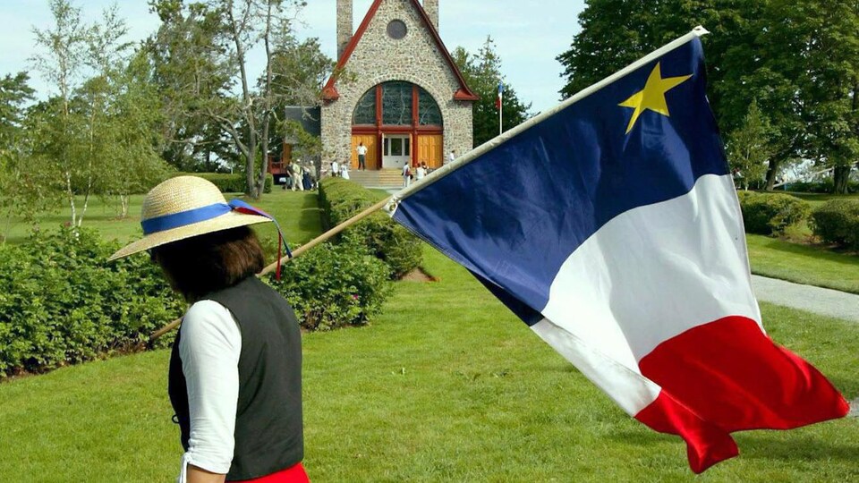 Jeanne (Doucet) Currie porte un drapeau acadien à Grand-Pré.