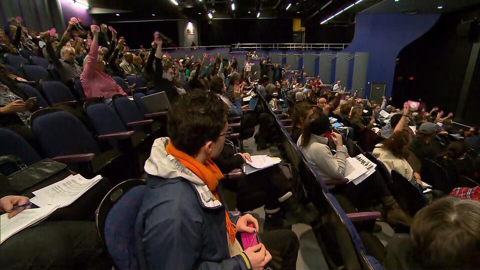 Les délégués sont assis dans un auditorium et votent.
