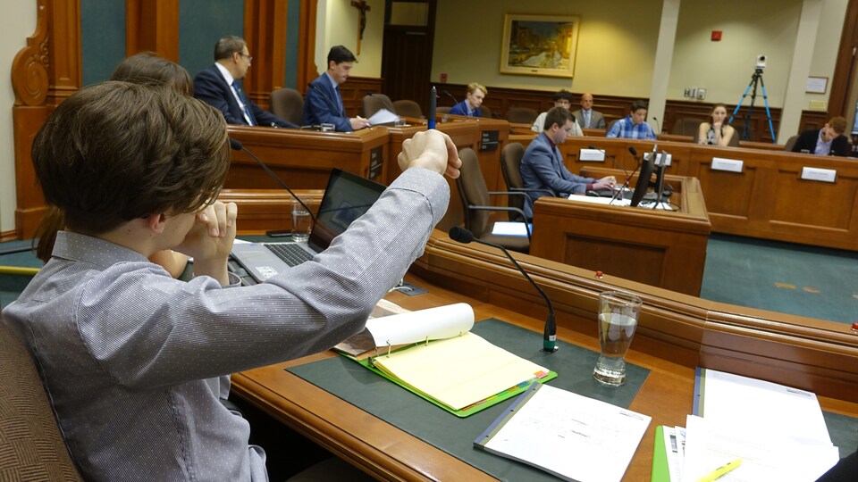 Un élève assis dans la salle du conseil de l'hôtel de ville de Sherbrooke lève la main pour obtenir un droit de parole.