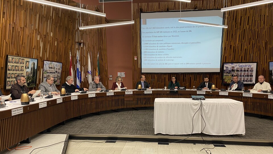 Les conseillers municipaux et la mairesse autour de la table du conseil municipal de Saguenay.