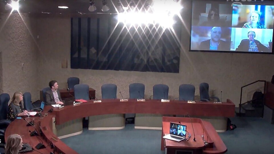 Les conseillers par vidéo sur un écran de la salle du conseil municipal.