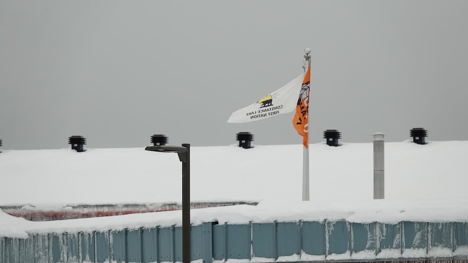 Deux drapeaux flottent sur un toit avec une couche de neige.