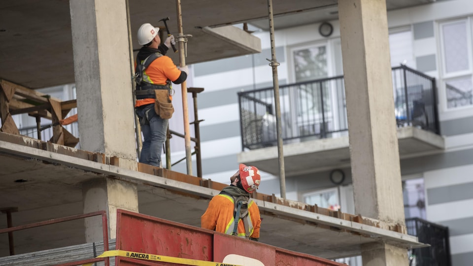 Deux travailleurs de la construction sur un chantier résidentiel.