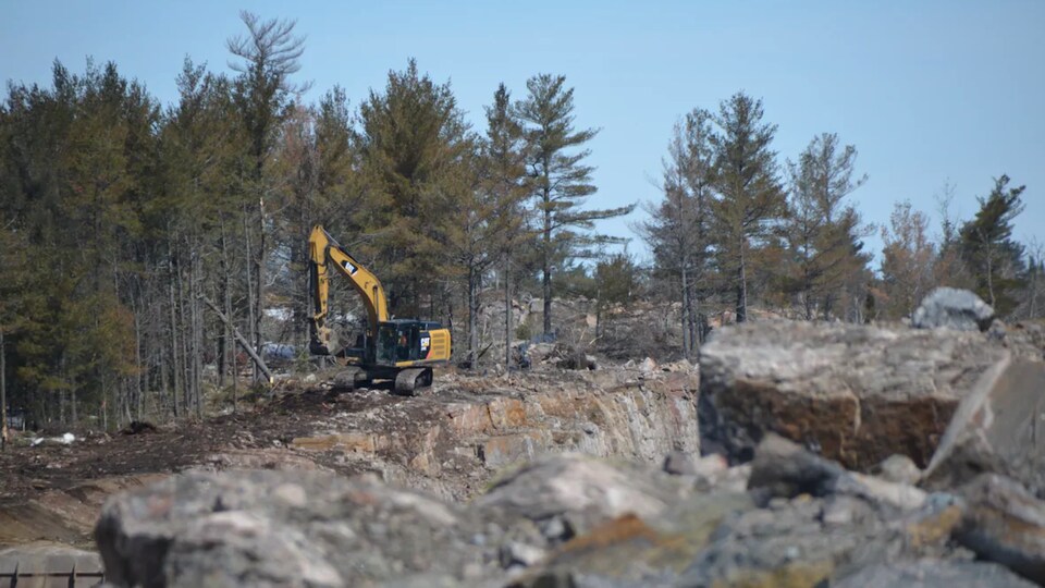 Une pelle mécanique sur un terrain rocailleux.