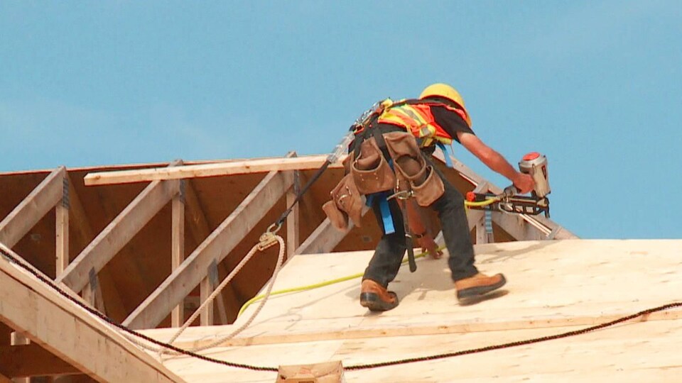 Un travailleur sur une toiture en construction.