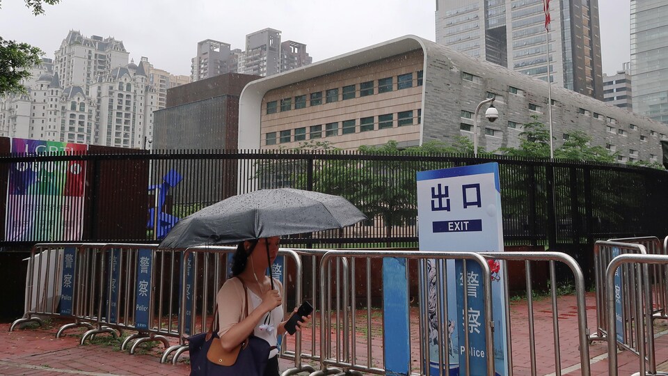Une femme qui marche devant le consulat se protège avec un parapluie
