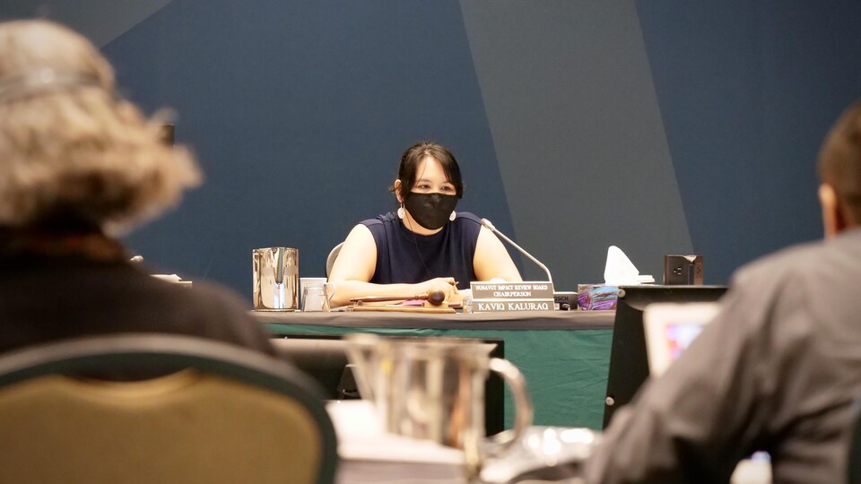 Une femme masquée derrière une table.
