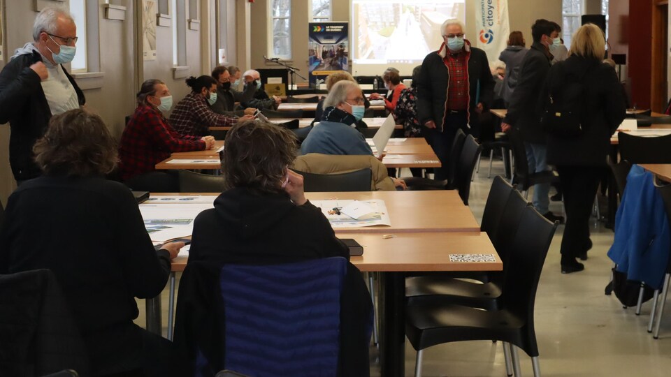 Des citoyens sont attablés en groupes de discussions sur le tramway au Collège Saint-Charles-Garnier.