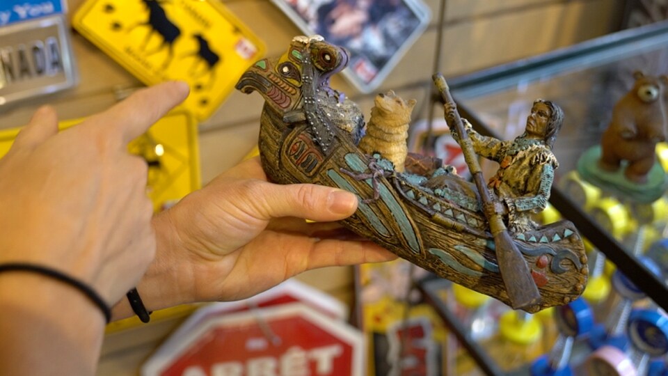 Une main montrant un objet. Un homme assis dans un canot qui pagaie.