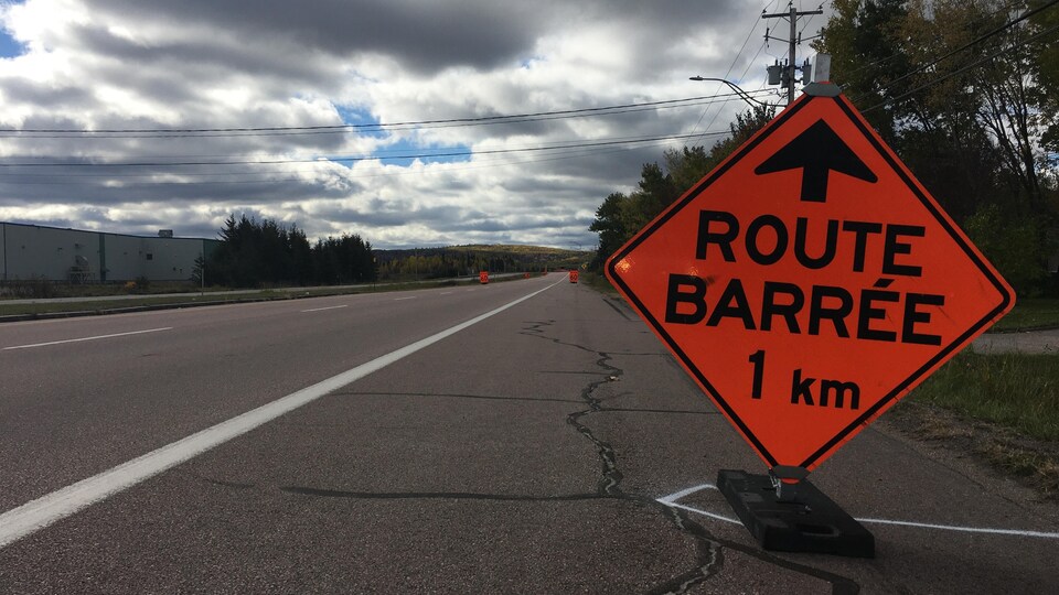 Un panneau « route barrée » prévient d'un éventuel barrage à 1 kilomètre.