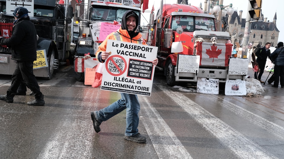 Un homme tient une pancarte contre le passeport vaccinal lors du convoi des camionneurs à Ottawa.