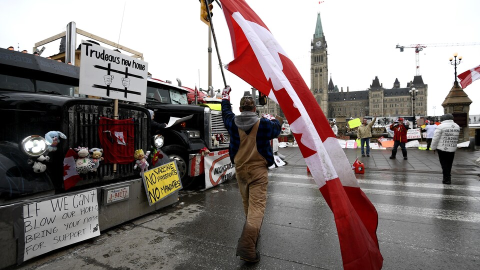 Un manifestant, devant le parlement, avec un drapeau du Canada.