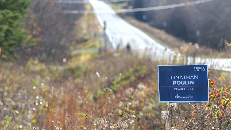 Une pancarte du candidat du Parti conservateur du Québec, Jonathan Poulin devant une route. 

