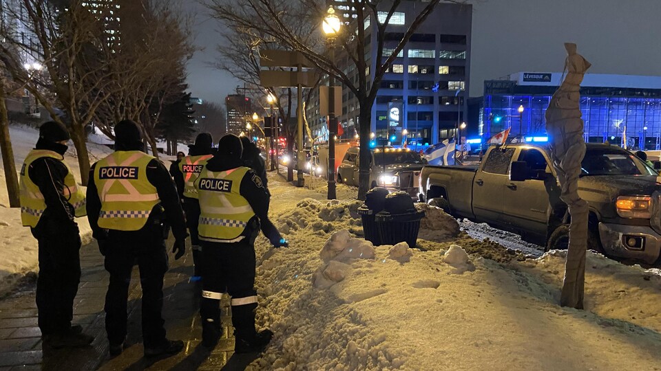 Des voitures et des picks aux abords de la colline Parlementaire à Québec. Des policiers sont présents sur le trottoir.