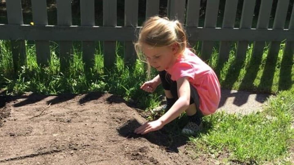 Une jeune fille plante des graines.