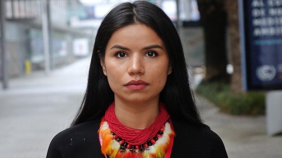 Portrait de Nina Gualinga qui regarde droit devant elle.