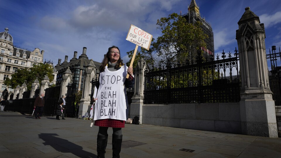 Une femme tient une pancarte devant le parlement britannique.
