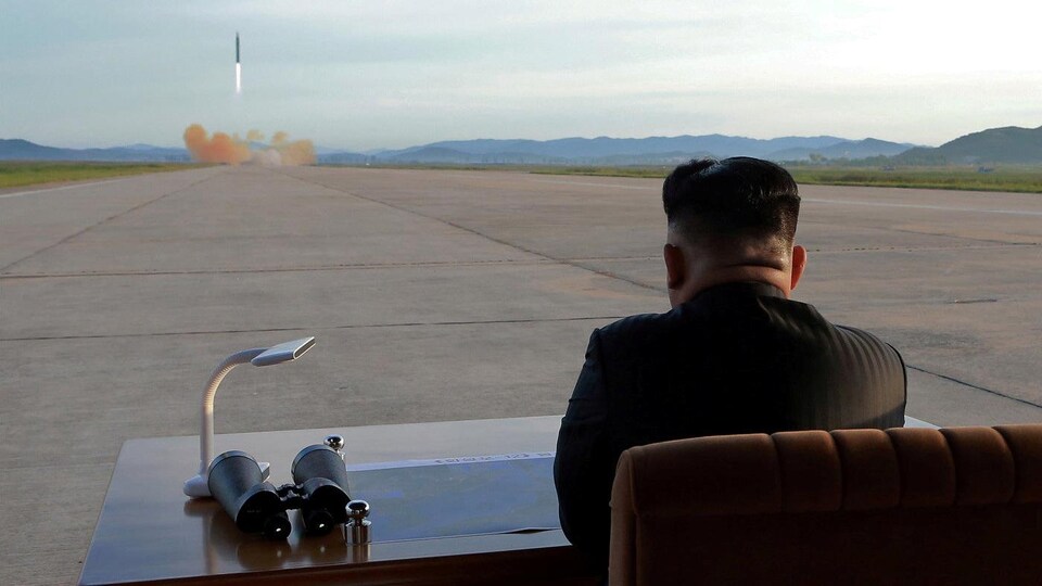 Le leader nord-coréen Kim Jong-un, vu de dos, regarde au loin une fusée décoller.
