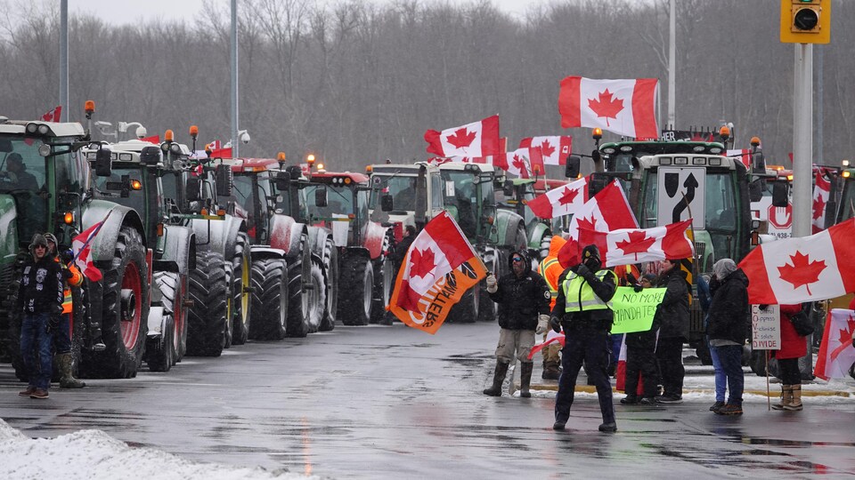 Des gens manifestent près de nombreux tracteurs stationnés.