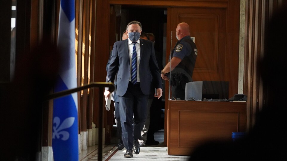 François Legault marche dans un couloir de du parlement.