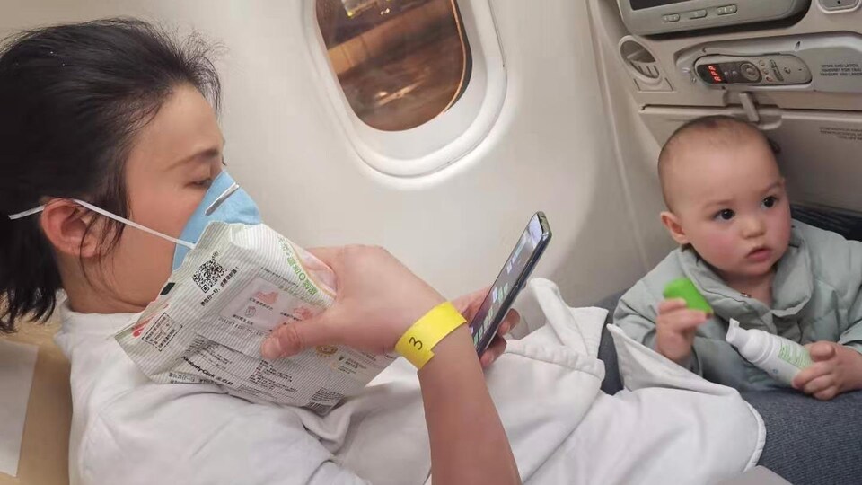 Une femme et un bambin à leurs sièges dans un avion.