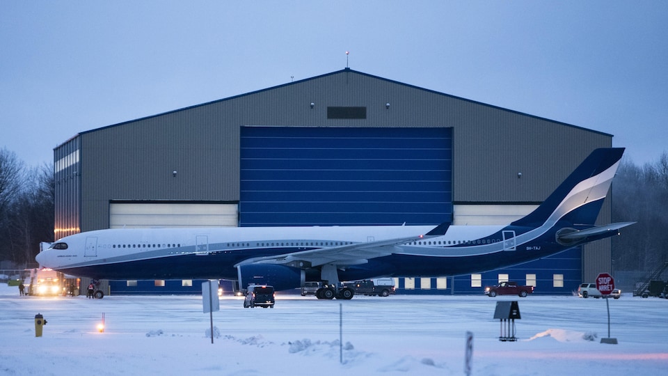 Un Airbus A330 devant un grand hangar.