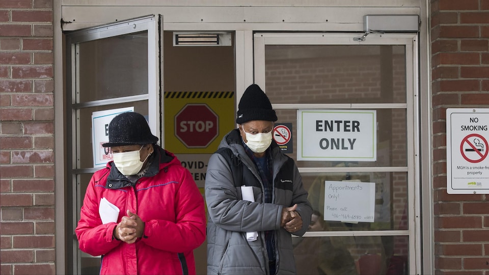 Deux personnes à l'extérieur d'un centre de dépistage portant un masque.