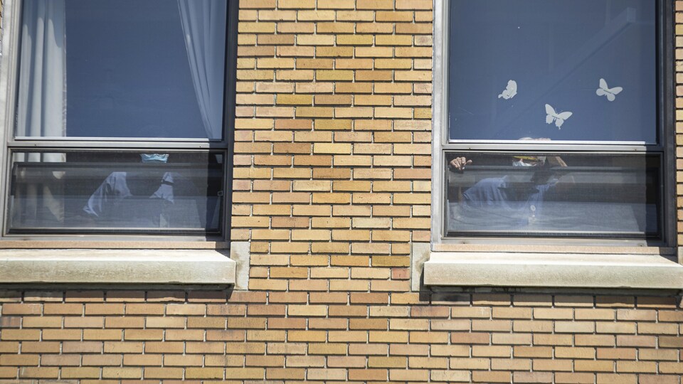 Deux personnes près d'une fenêtre ouverte d'un établissement.