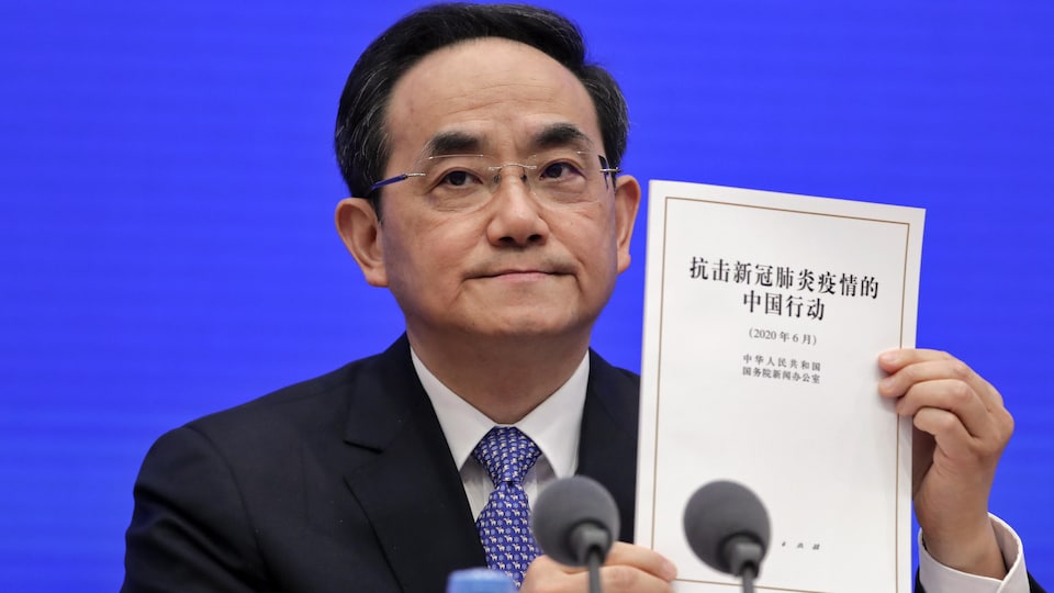Xu Lin, vice-directeur du département de la publicité du Parti communiste, montre une copie du livre blanc sur la lutte contre la COVID-19 lors d'une conférence de presse au bureau d'information du Conseil d'État, à Pékin, dimanche.