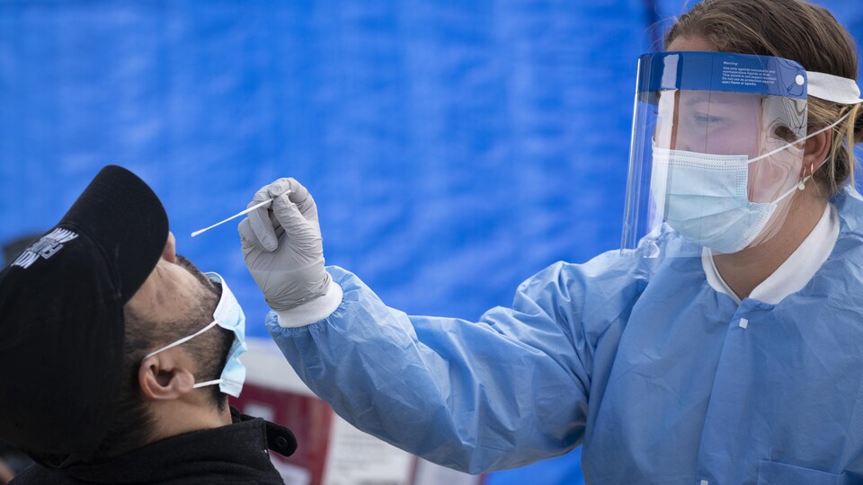 Une professionnelle de la santé effectue un test de dépistage du coronavirus dans une clinique mobile du quartier Saint-Michel à Montréal.