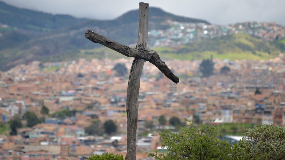 Une croix en bois en avant-plan et la ville au fond.