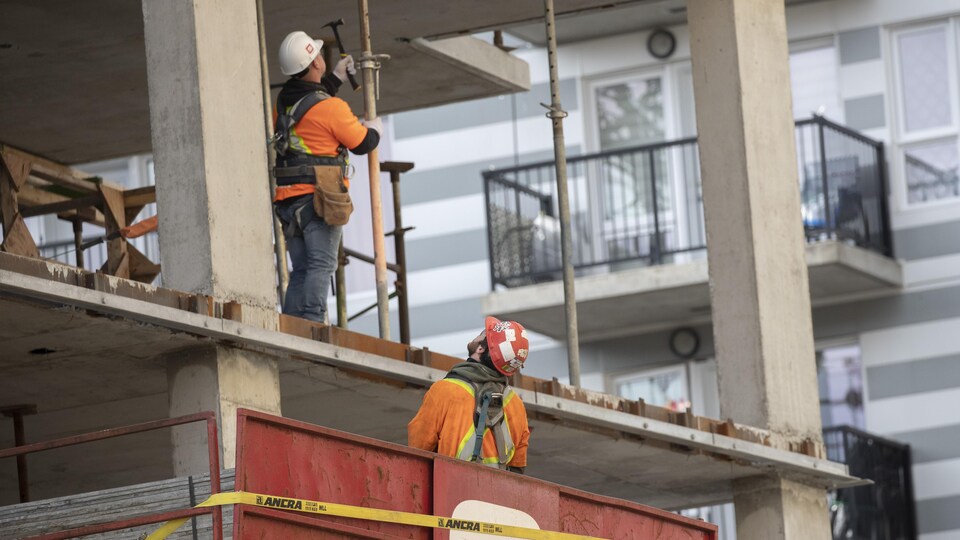 Deux employés du domaine de la construction sur un chantier.