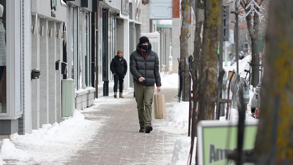 Un homme qui porte un couvre-visage déambule sur la rue Saint-Germain à Rimouski.