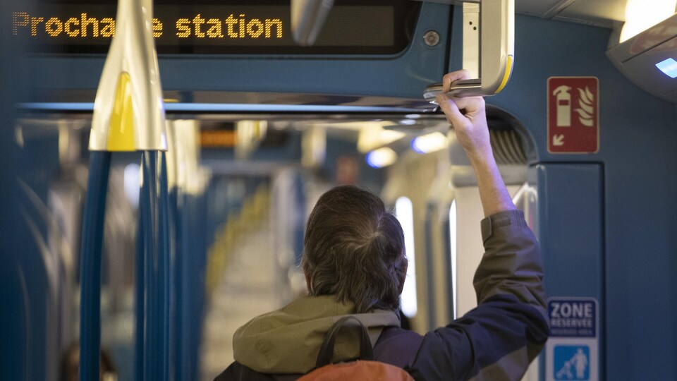 Une personne se tient dans une rame de métro.