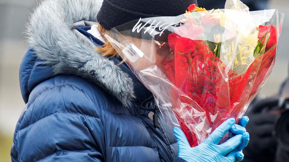 Une femme pleure en tenant un bouquet de fleur.
