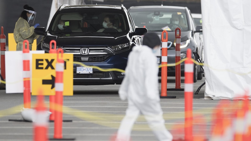 Des automobilistes sont garés avec du personnel infirmier autour.