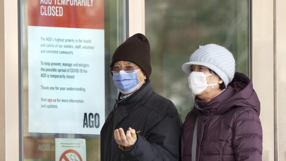 Deux aînés portant un masque passent devant un musée fermé à Toronto.