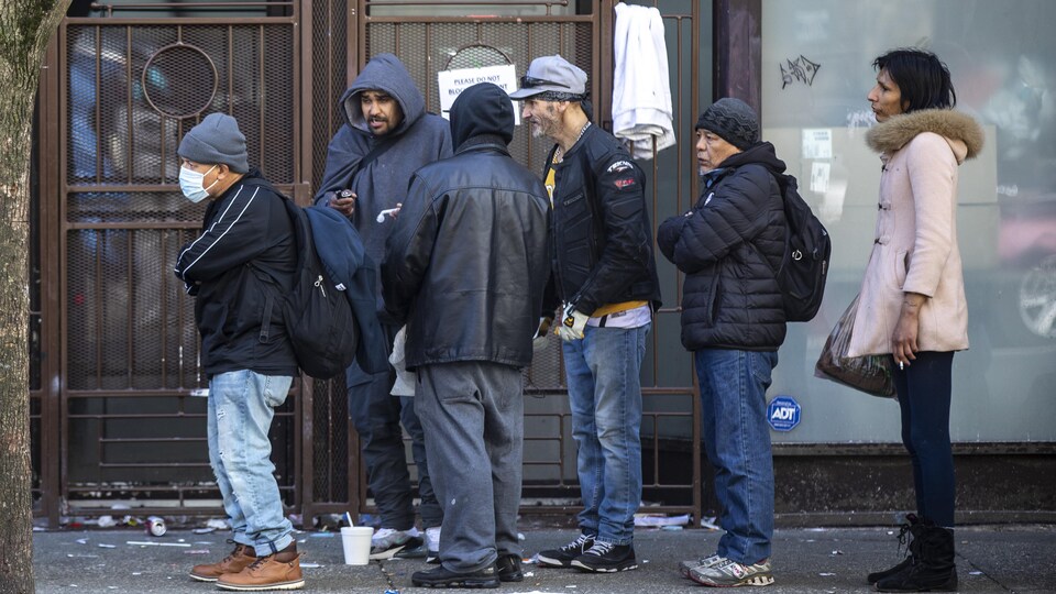 Des gens font la file dans le quartier du Downtown Eastside à Vancouver. 