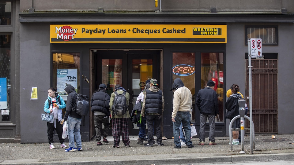 Des gens font la file pour encaisser leurs chèques dans le quartier du Downtown Eastside à Vancouver. 