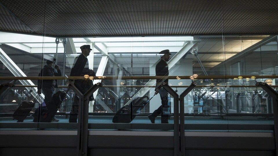 Des pilotes et un passager marchent à l'aéroport de Vancouver.