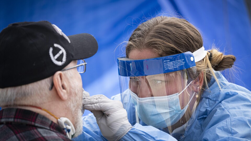 Une professionnelle de la santé effectue un test de dépistage de la COVID-19 sur un patient âgé.