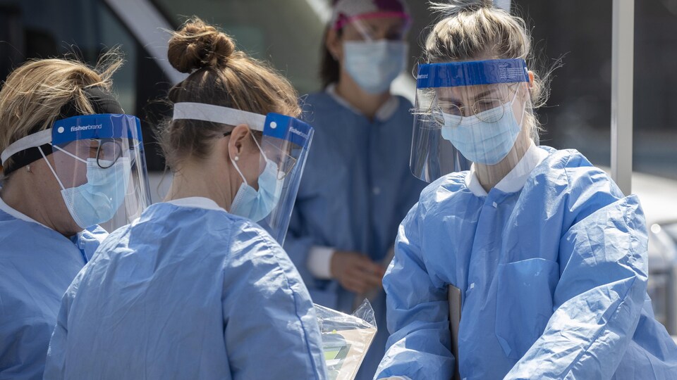 Des professionnelles de la santé portant leur blouse bleue et un masque.