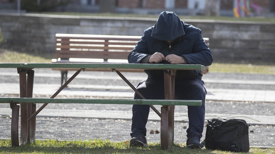Un homme assis à une table de pique-nique dans un parc à Montréal.