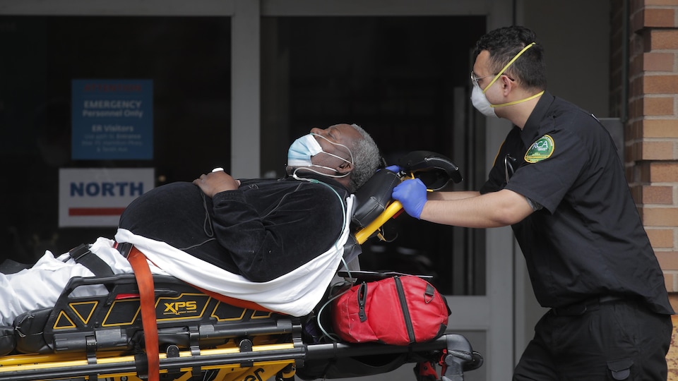 Un ambulancier amène un patient victime de la COVID-19 dans un centre d'urgence au Maimonides Medical Center, à New York.