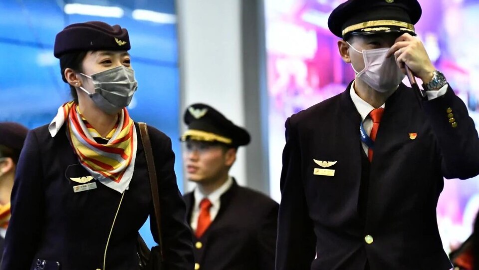 Des pilotes chinois portent des masques recouvrant leur bouche et leur nez.