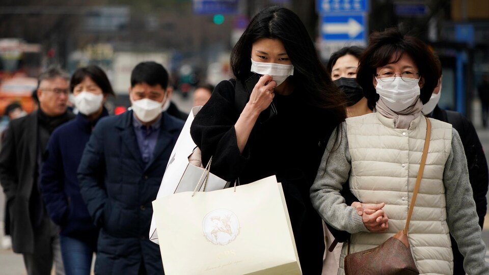 Des piétons portant des masques marchent dans les rues de Séoul.  